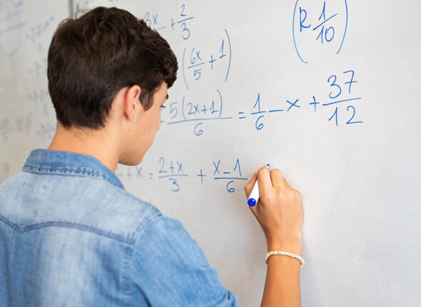 College student solving math equation on white board